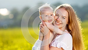 Happy family mother and baby hugging nature in summer