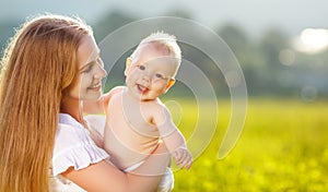 Happy family mother and baby hugging nature in summer