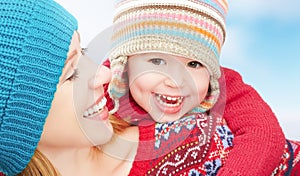 Happy family mother and baby little daughter playing in winter