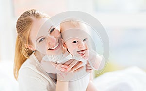 Happy family mother with baby playing and hug in bed