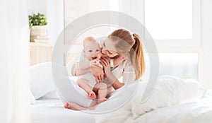 Happy family mother with baby playing and hug in bed