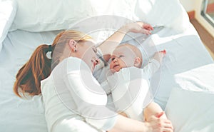 Happy family mother with baby playing and hug in bed