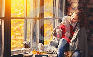 Happy family mother and baby playing and laughing at window in f