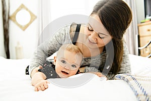 Happy family. Mother and baby playing and smiling under a blanket