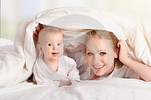 Happy family. Mother and baby playing under blanket