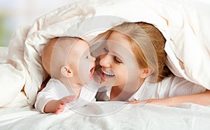 Happy family. Mother and baby playing under blanket photo