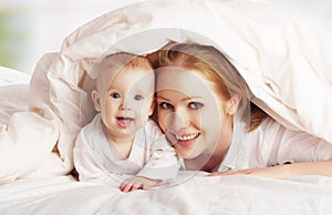 Happy family. Mother and baby playing under blanket