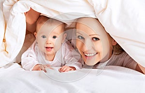 Happy family. Mother and baby playing under blanket