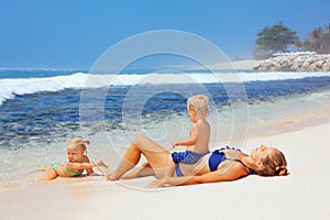 Happy family - mother, baby son, daughter sunbathing on sea beach