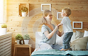 Happy family mother and baby son toddler laughing in bed