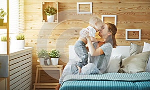 Happy family mother and baby son toddler laughing in bed