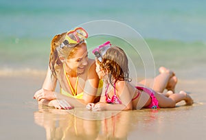 Happy family mother and chid daughter in masks on beach in summer