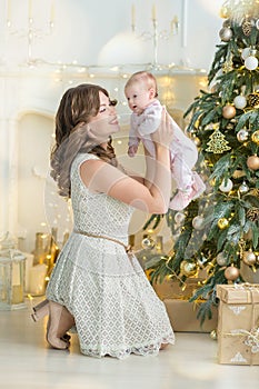 Happy family mother and child baby boy on Christmas morning at the tree with gifts, home decoration, interior house