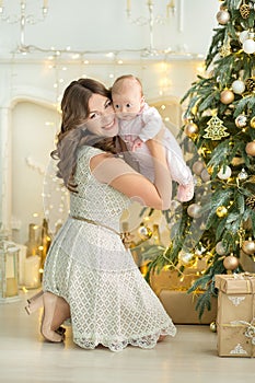 Happy family mother and child baby boy on Christmas morning at the tree with gifts, home decoration, interior house