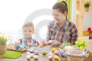 Happy family mother and child boy paints eggs for Easter at home. Family celebrating Easter