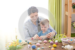 Happy family mother and child boy paints eggs for Easter at home. Family celebrating Easter