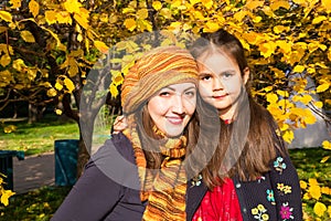 Happy family: mother and child daughter have fun in autumn on autumn park. Young Mother and kid girl hugging in leaves at fall.