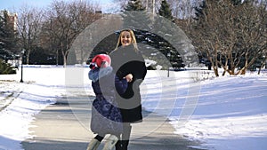 Happy family mother and child daughter having fun, playing at winter walk outdoors