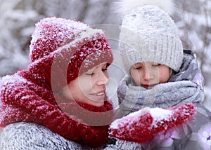 Happy family mother and child daughter having fun, playing at winter walk outdoors