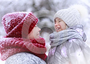 Happy family mother and child daughter having fun, playing at winter walk outdoors