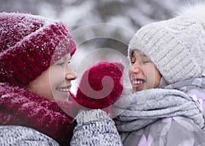 Happy family mother and child daughter having fun, playing at winter walk outdoors