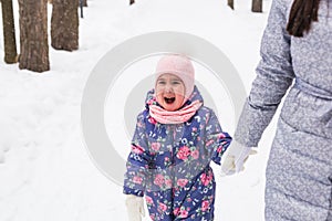 Happy family mother and child daughter having fun, playing at winter walk outdoors