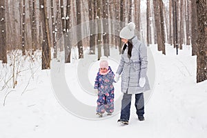 Happy family mother and child daughter having fun, playing at winter walk outdoors