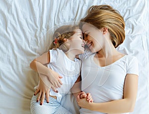 Happy family mother and child daughter laugh in bed