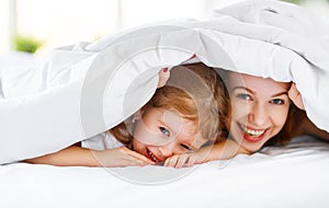 Happy family mother and child daughter laugh in bed
