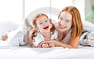 Happy family mother and child daughter laugh in bed