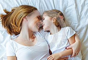 Happy family mother and child daughter laugh in bed