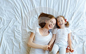 Happy family mother and child daughter laugh in bed