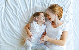 Happy family mother and child daughter laugh in bed