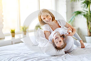 Happy family mother and child daughter laugh in bed