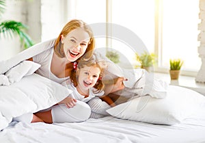 Happy family mother and child daughter laugh in bed photo