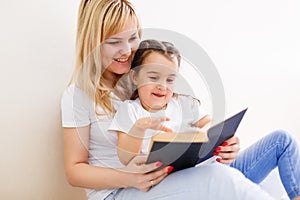 Happy family mother child daughter little girl reading a book by the window