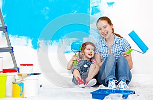 Happy family mother and child daughter making repairs, paint wal