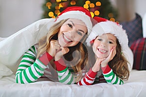 Happy family mother and child daughter in pajamas opening gifts