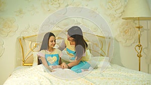 Happy family mother and child daughter play and laugh in bed