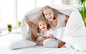 Happy family mother and child daughter laugh in bed