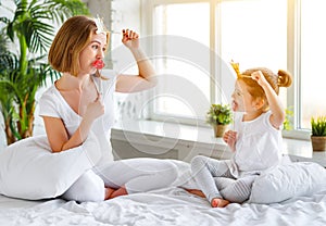 Happy family mother and child daughter playing with crowns in pr