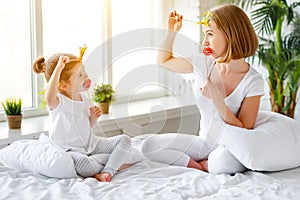 Happy family mother and child daughter playing with crowns in pr