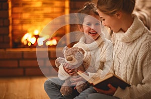 Happy family mother and child daughter read a book on winter ev