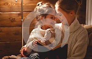 Happy family mother and child daughter read a book on winter e