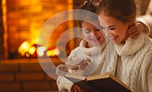 Happy family mother and child daughter read a book on winter ev
