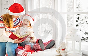 Happy family mother and child daughter reading book on winter wi