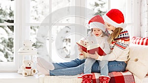 Happy family mother and child daughter reading book on winter wi