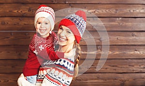 Happy family mother and child girl hugs at wooden background