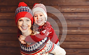 Happy family mother and child girl hugs at wooden background