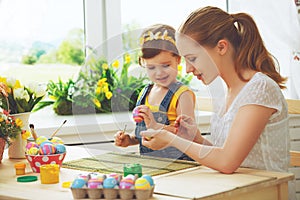 Happy family mother and child girl paints eggs for Easter